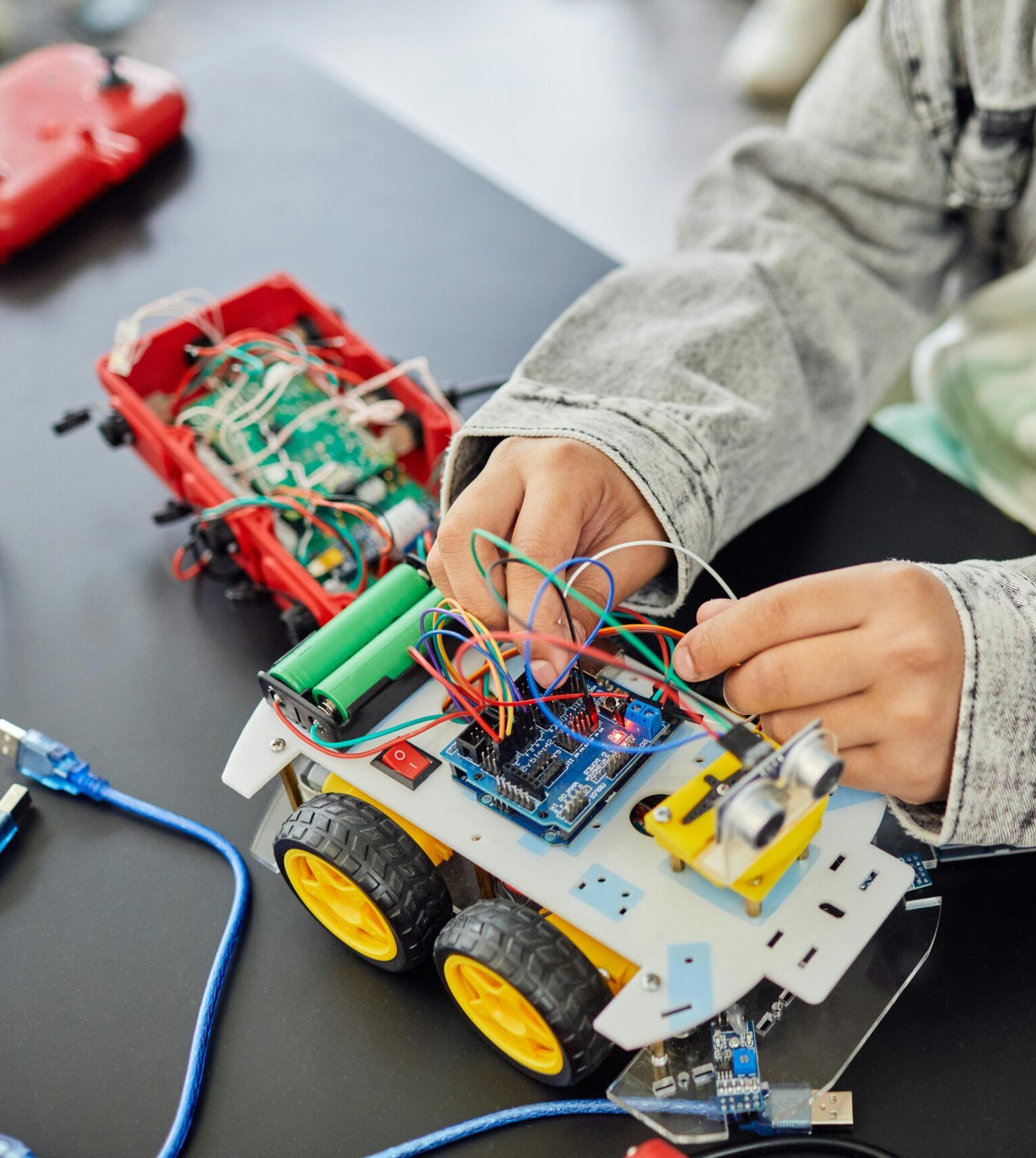 Young student assembling a toy car with electronic components, focusing on STEM education.